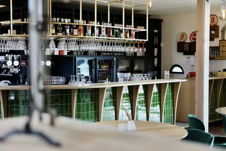 Bar met groene tegels en glazenrekken in lichte ruimte met houten accenten